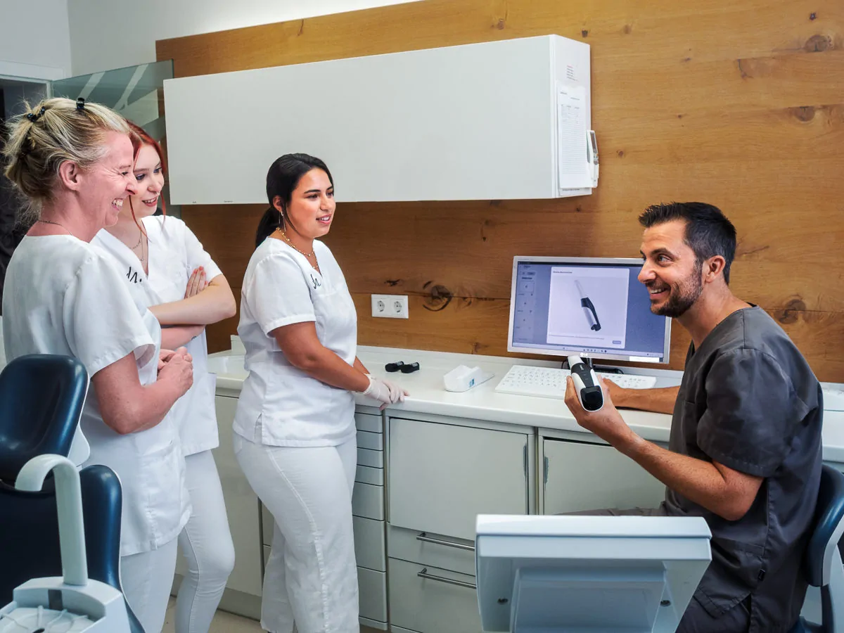 Dr. Henninger erklärt drei neuen Mitarbeiterinnen wie der Intraoralscanner funktioniert.