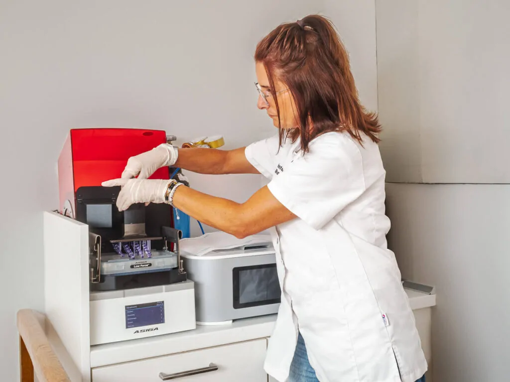Zahntechnikerin mit einer CAD-Maschine im Dentallabor.