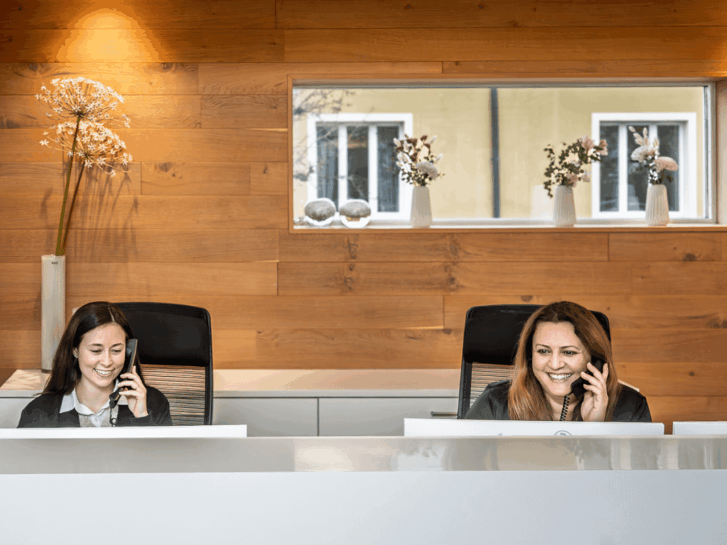 Zwei Mitarbeiterinnen telefonieren am Empfang.