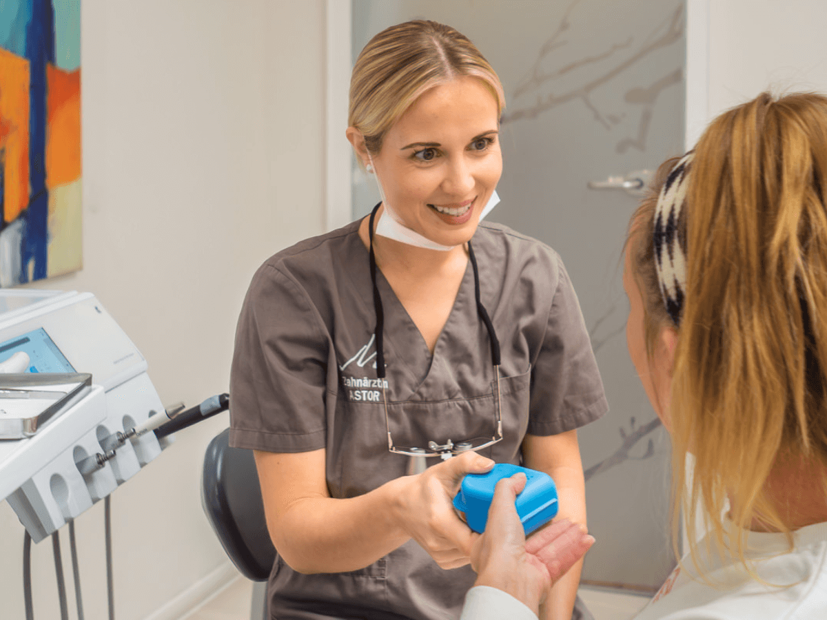 Zahnärztin Vanessa Debatin überreicht Patientin die HarmonieSchiene in einer Box.