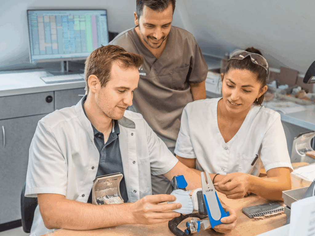 Dr. Henninger bespricht individuellen Implantatkronen mit zwei Zahntechnikern im hauseigenen Labor.